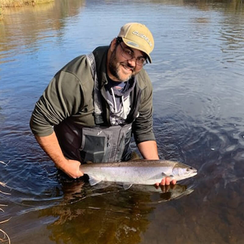 Patrick Poirier in the water holding a fish