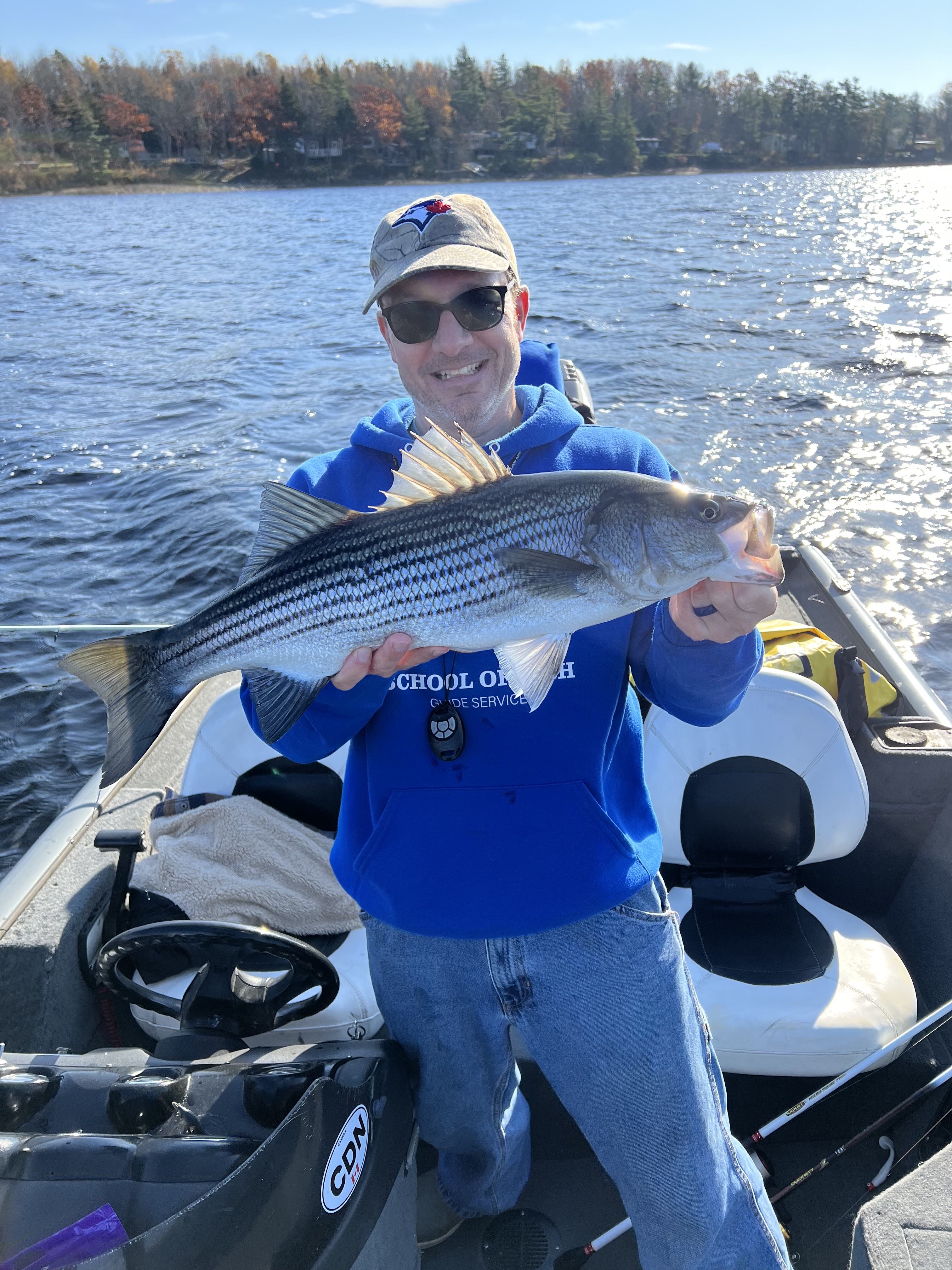 ryan holding a striped bass in front of the water