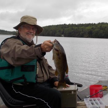 Carroll in a boat with a smallmouth bass